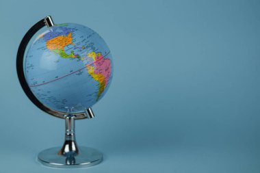 Küçük, dekoratif bir küre zarif bir şekilde canlı mavi bir masaya yerleştirildi. Dünyamızın çeşitli ülkeleri ve kıtalarını gözler önüne seriyor.