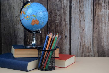 Güzelce hazırlanmış bir küre, düzgünce düzenlenmiş uzun bir kitap yığınının üzerinde duruyor. Mükemmel bir hayat kompozisyonu sergiliyor.
