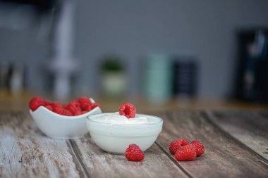 Masanın üzerinde beyaz yoğurt, yakından ahududu, mutfakta sağlıklı kahvaltı. Yüksek kalite fotoğraf