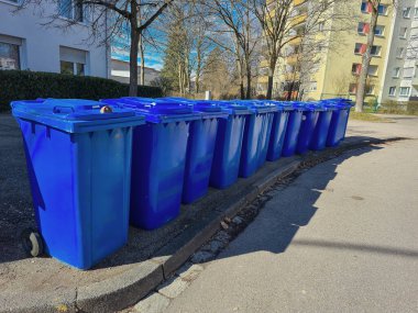 Geri dönüşümün önemini ve önemini vurgulayan bir sıra mavi geri dönüşüm çöpü şehir sokaklarında düzgünce yerleştirildi.