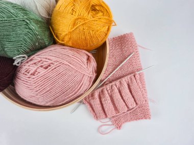 Beyaz arka planda renkli iplikler seriliydi. Yumuşak liflerin dokusu açıkça görülüyor, sıcak ve samimi bir ortam yaratıyor. El sanatları, örgü örme, tekstil tasarımı ve yaratıcılık.