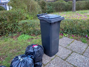 Kahverengi kutular biyolojik atıklar için, gri kutular ise karışık atıklar için. Yeşil alanlar, bir kaldırım ve bir patika var. Tema, ekoloji, atık imhası ve kentsel çevrenin temizliği..