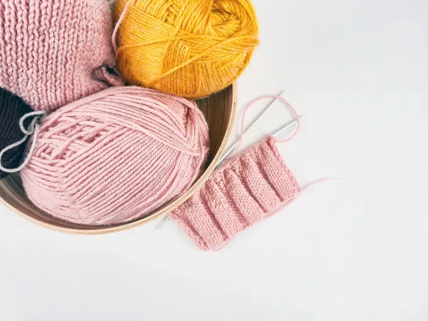 Beyaz arka planda renkli iplikler seriliydi. Yumuşak liflerin dokusu açıkça görülüyor, sıcak ve samimi bir ortam yaratıyor. El sanatları, örgü örme, tekstil tasarımı ve yaratıcılık.