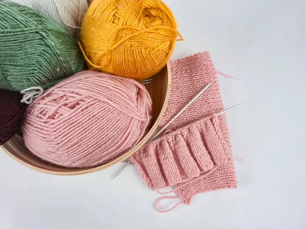 Beyaz arka planda renkli iplikler seriliydi. Yumuşak liflerin dokusu açıkça görülüyor, sıcak ve samimi bir ortam yaratıyor. El sanatları, örgü örme, tekstil tasarımı ve yaratıcılık.