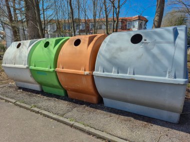 Parkta çevre dostu atık imhası için renkli geri dönüşüm kutularından oluşan canlı bir sıra yerleştirildi.