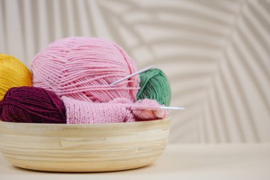 Ahşap bir kasede renkli iplik toplarından oluşan canlı bir karışım örgü ve el işi meraklıları için mükemmel.