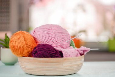 Kırsal ahşap bir kasede sergilenen iplik topları ve örgü iğnelerinden oluşan güzel bir koleksiyon.