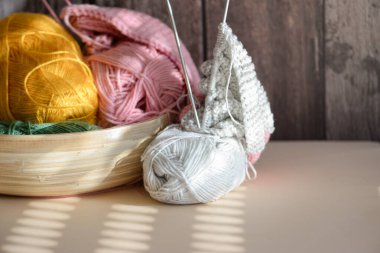 Doğal ışıkla aydınlatılmış çeşitli canlı iplikler ve örgü iğnelerinin yer aldığı samimi ve sıcak bir sahne.