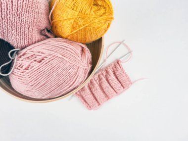 Beyaz arka planda renkli iplikler seriliydi. Yumuşak liflerin dokusu açıkça görülüyor, sıcak ve samimi bir ortam yaratıyor. El sanatları, örgü örme, tekstil tasarımı ve yaratıcılık.