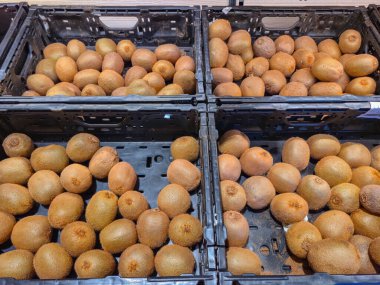 Canlı ve davetkar taze kiwifruit sergisi siyah sandıklar içinde zarif bir şekilde düzenlendi, hepsi satılmaya hazır.
