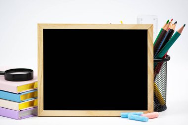 Yaratıcı bir şekilde düzenlenmiş çalışma alanı geniş bir karatahta, renkli kırtasiye ve düzenli kitaplar içerir.