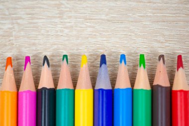 Rengarenk bir kalem dizisi canlı renkler sergiliyor ahşap bir arka planda zarif bir şekilde düzenlenmiş.