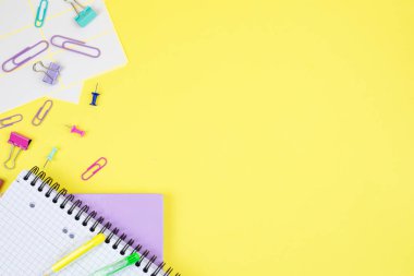 Yaratıcı projeler ve tasarımlar için ideal parlak sarı arka planda ofis malzemelerinin rengarenk düzenlenmesi