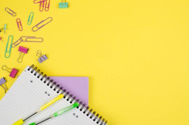 Renkli not defterleri ve neşeli klipler gibi, hoş sarı bir ton içeren canlı bir kırtasiye malzemesi dizisi.