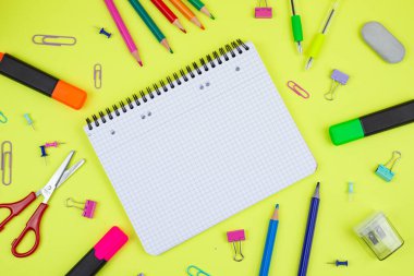 Yaratıcı görevler için boş bir defterin yanı sıra renkli kırtasiye sergilenen ilham verici ve canlı bir çalışma alanı.