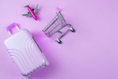 Şık ve şık bir bavul, uçak ve alışveriş arabasının canlı bir arka planda sergilenmesi.