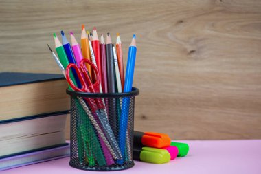 Masanın üzerinde renkli kalemler, makas ve kalemler de dahil olmak üzere çeşitli kırtasiye malzemelerinin canlı bir çeşitliliği vardır.