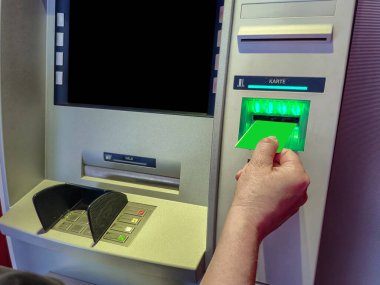Bir kadın eli, ATM kartı okuyucusuna mavi bir kredi kartı yerleştiriyor. Kadınlar manikür ve banka kartıyla el ele tutuşur. Yüksek kalite fotoğraf