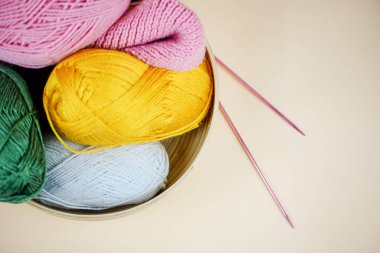 Yün yumağı ve örgü iğnelerinden oluşan canlı bir karışım bir kaseye konmuş, el yapımı projeler için mükemmel..
