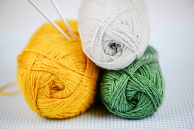 Sarı, beyaz ve yeşil renkli üç iplik yumağı örgü ve el işi projeleriniz için ideal.