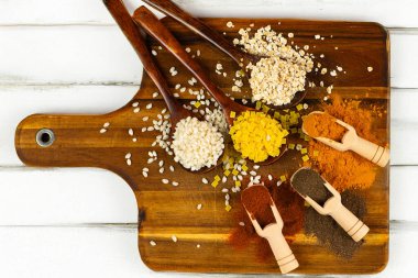 Renkli bir aromatik baharat dizisi ve kırsal bir ahşap tahtada ustalıkla düzenlenmiş besleyici tanecikler.