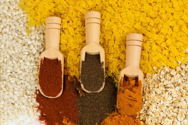 Göz kamaştırıcı renkli baharatlar serisi, ahşap kepçelerle çok güzel düzenlenmiş, canlı bir arka planda.