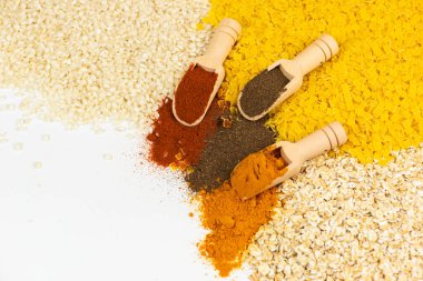 Gelişmiş mutfak yaratıcılığı için ahşap kepçelerle ustalıkla düzenlenmiş renkli baharat ve tahıllar dizisi.