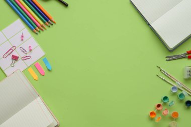 Kırtasiye malzemelerinin ve sanat malzemelerinin yeşil zemin üzerinde canlı bir düzenleme, yaratıcı projeler için ideal..