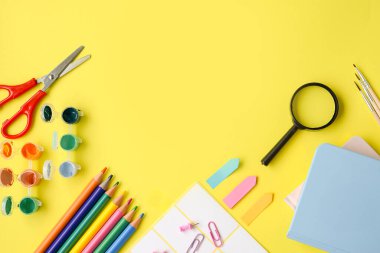 Canlı ve renkli bir sanat ve el işi malzemesi koleksiyonu neşeli sarı bir yüzey üzerinde titizlikle düzenlenmiştir.