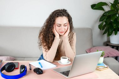 Motive olmuş bir kadın evde çalışıyor ya da uzaktan çalışıyor. Yaratıcılığa ilham veren şık bir dekorda kahvenin tadını çıkarıyor.