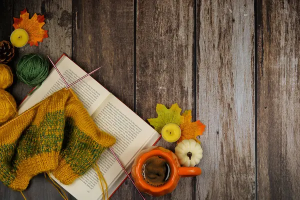 Sıcak ve davetkar bir iç mekan sahnesi. İçinde samimi bir kitap, canlı bir hikaye, lezzetli bir kahve ve renkli sonbahar yaprakları var.