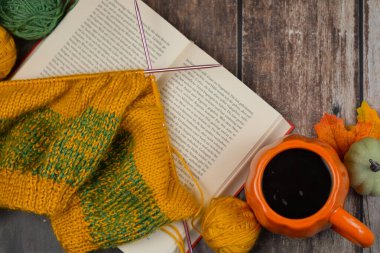 Örgü malzemeleri, ilginç bir kitap ve sıcak bir içecek içeren sakin bir sahne. Sıcak bir sonbahar için ideal.