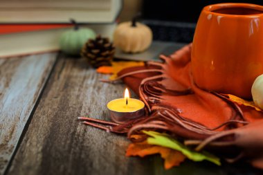 Sıcak bir sonbahar ortamında bir mum, dekoratif balkabağı ve hoş tekstil eşliğinde davetkar bir ortam için toplanın.