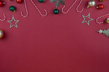 Çekici Noel süsleri, renkli şeker kamışları ve parlak kırmızı arka planda parıldayan yıldızlar.