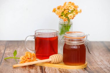 Güzel ve büyüleyici bir bal gösterisi, bitkisel çay, ve kırsal bir ahşap masada taze çiçekler.