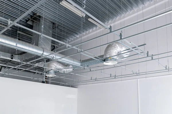 Ventilation and air conditioning system on the ceiling of an industrial building, metal ventilation pipes