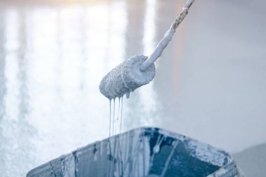 Bir boya silindirinin yakın çekimi, gri boya silindirden aşağı akıyor.