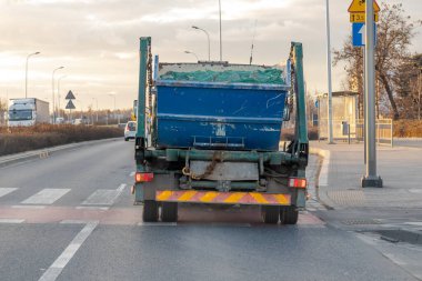 Garbage truck rides through the city, taking out a container with bulky garbage