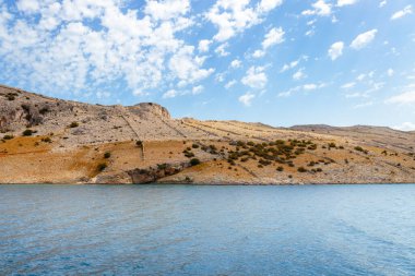 Mavi denizin kıyısındaki kumlu ıssız adalar ve tepeler, ıssız adaların manzara fotoğrafları, üzerinde büyük kayalar. Hırvatistan 'ın Pag Adası