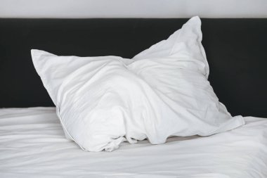 Kırışmış beyaz bir yastık uyuduktan sonra yatağın üzerinde uzanıyor.
