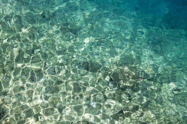 Soyut deniz suyu akışı arka planda güneş ışınları yansımaları, güneşli bir günde şeffaf deniz suyu turkuvaz rengi.