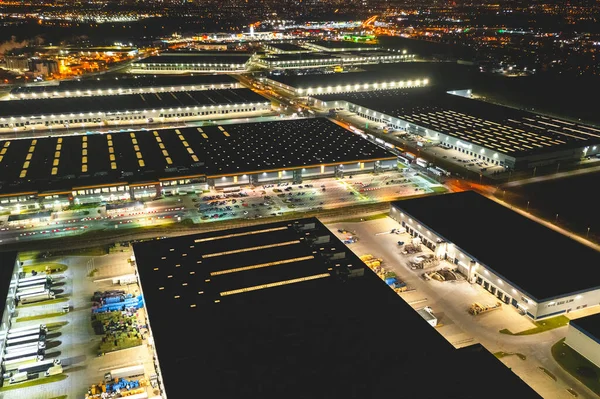 Aerial view of a warehouse of goods at night. Aerial view of industrial area, logistics warehouses and many trucks at night