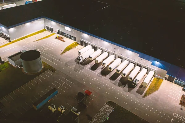 夜间从空中俯瞰一仓库货物 许多装有拖车的仓库和卡车停在停车场 等待装运 以便在全国各地进一步分发货物 免版税图库图片