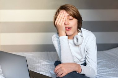 Dizüstü bilgisayarın önünde stresli bir genç çocuk..