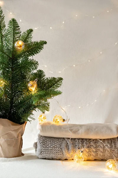 stock image Elegant Christmas spruce, fir tree with warm sparkling garland lights in front of neutral light wall. Christmas, New Year holidays celebration