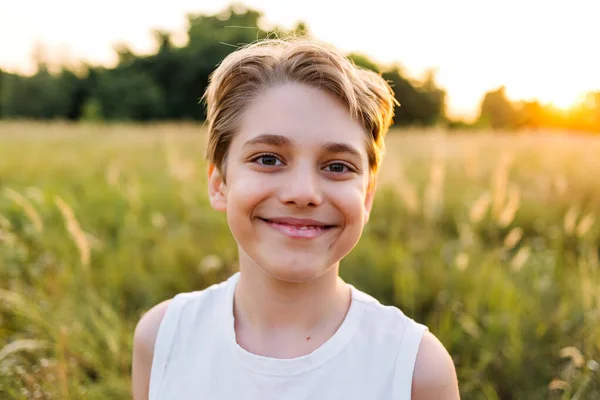 Portrait of happy smiling teenager boy in nature at sunset