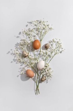 Aesthetic Easter composition, floral spring bouquet, natural color eggs on a light neutral background. Holiday greeting card design template