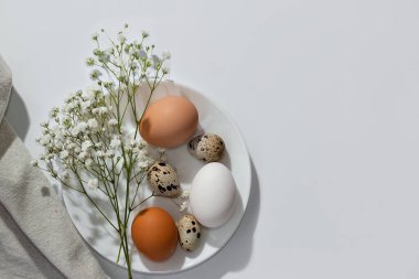 Aesthetic minimalist Easter table setting, eggs and flowers on white plate, on a neutral background. Elegant nordic spring template or banner, copy space