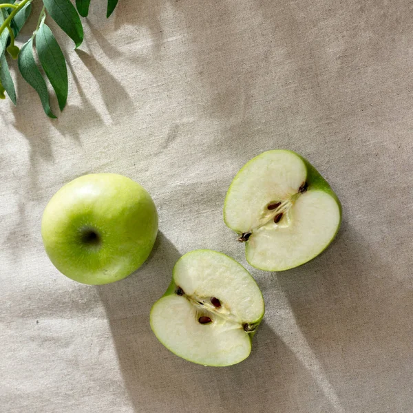 Green cut apples on a table with sunlight shadows, aesthetic lifestyle composition, flat lay, copy space