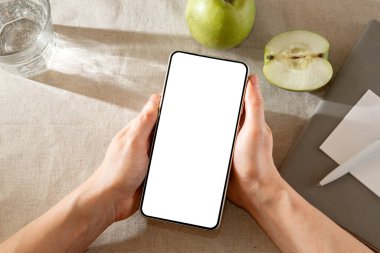 Cep telefonu bir kişinin elinde boş beyaz ekran, kopyalama alanı olan minimalist yaşam tarzı iş şablonu ile modellenir